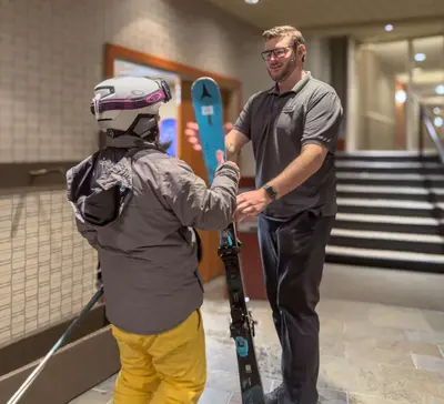 a man standing next to a man with skis at Listel Whistler, a Coast Hotel in Whistler