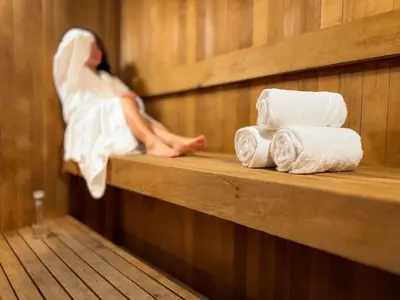 a woman sitting on a shelf in a sauna with towels at Listel Whistler, a Coast Hotel in Whistler