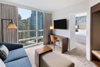 a living room with a couch and a desk and a large window at Hilton Vancouver Downtown, BC, Canada in Vancouver