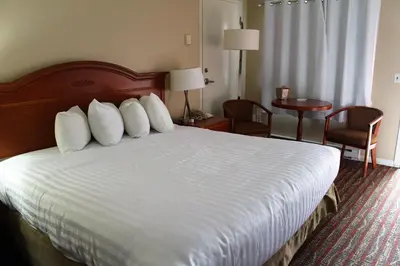 a hotel room with a bed with white sheets and pillows at Ramada by Wyndham Campbell River in Campbell River