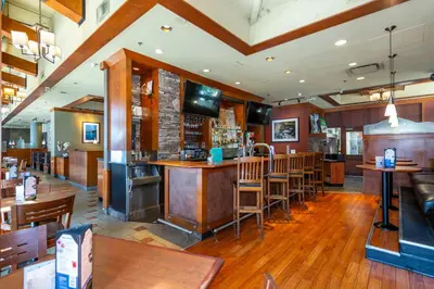 a bar in a restaurant with wooden tables and chairs at Grand Park Hotel & Suites Downtown Vancouver, an Ascend Collection Hotel in Vancouver
