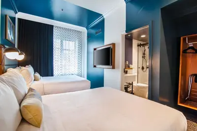 a hotel room with two beds and a television at Hotel Belmont Vancouver - MGallery Collection in Vancouver