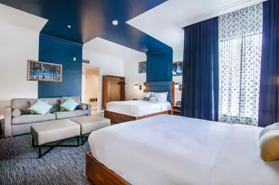 a hotel room with two beds and a couch at Hotel Belmont Vancouver - MGallery Collection in Vancouver