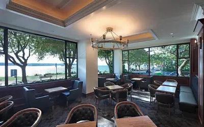 a restaurant with tables and chairs and large windows at The Sylvia Hotel in Vancouver