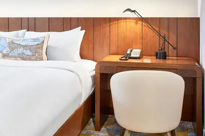 a hotel room with a bed and a desk with a chair at Metropolitan Hotel Vancouver in Vancouver