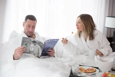 a man and woman sitting in bed reading a magazine at OPUS Vancouver in Vancouver