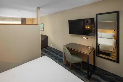 a hotel room with a bed and a desk with a television at Accent Inns Vancouver Airport in Richmond