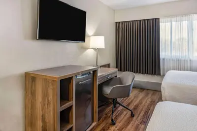 a hotel room with a desk and a television at Days Inn by Wyndham Victoria On The Harbour in Victoria