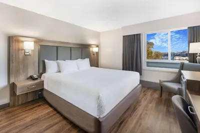 a hotel room with a bed and a desk and a window at Days Inn by Wyndham Victoria On The Harbour in Victoria