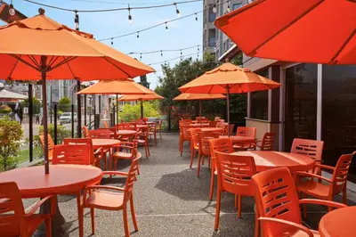 a row of tables and chairs with orange umbrellas at Days Inn by Wyndham Victoria On The Harbour in Victoria