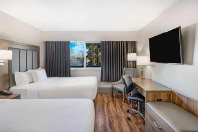 a hotel room with two beds and a desk at Days Inn by Wyndham Victoria On The Harbour in Victoria