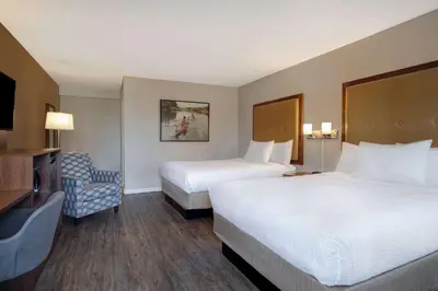 a hotel room with two beds and a chair at Days Inn by Wyndham Victoria Uptown in Victoria