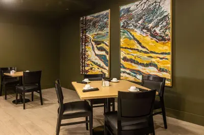 a dining room with a table and chairs and a painting at DoubleTree by Hilton Calgary North in Calgary