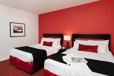 two beds in a hotel room with red walls at Moda Hotel in Vancouver