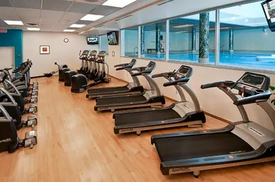 a row of treadmills in a gym with a pool at Hotel Grand Pacific in Victoria