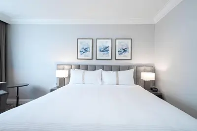 a bedroom with a large white bed with two lamps at The Sutton Place Hotel Vancouver in Vancouver
