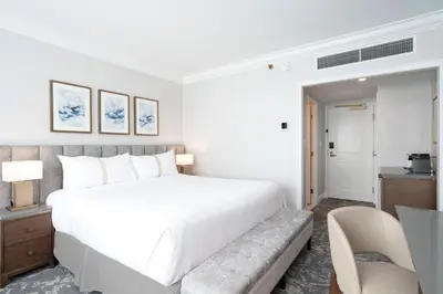 a bedroom with a large white bed and a desk at The Sutton Place Hotel Vancouver in Vancouver