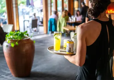 a woman holding a tray with drinks on it at Brentwood Bay Resort & Spa in Brentwood Bay