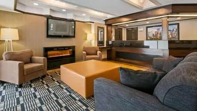 a living room with a couch and chairs and a tv at Best Western Airport Inn in Calgary
