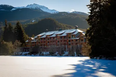 a large building in the mountains with snow on the ground at Nita Lake Lodge in Whistler