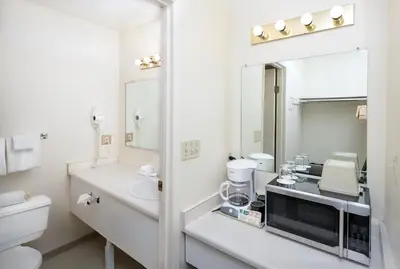 a white bathroom with a sink and a mirror at Cassandra Hotel in Vancouver