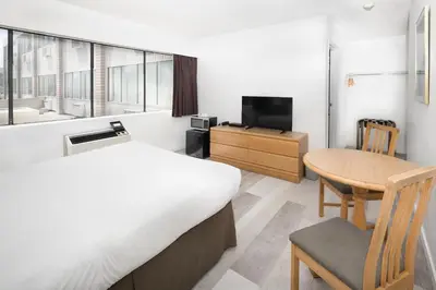 a bedroom with a bed and a table and a tv at Cassandra Hotel in Vancouver