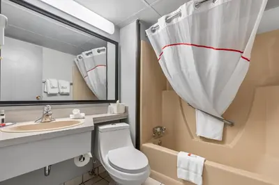 a bathroom with a toilet and a sink and a mirror at Emerald Hotel & Suites Calgary Airport in Calgary