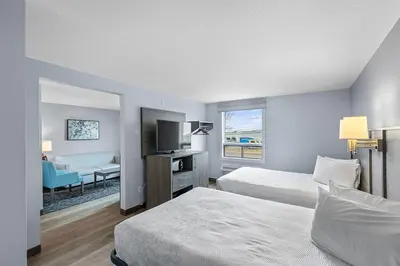 a hotel room with two beds and a flat screen tv at Emerald Hotel & Suites Calgary Airport in Calgary