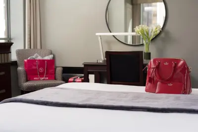 a hotel room with a bed with a red bag on it at The St. Regis Hotel in Vancouver