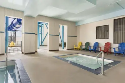 a pool in a room with chairs and a table at Travelodge by Wyndham Edmonton West in Edmonton