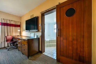 a hotel room with a desk and a sliding door at Grand Park Hotel Vancouver Airport, an Ascend Collection Hotel in Richmond