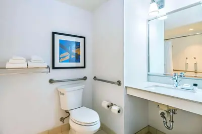 a bathroom with a toilet and a sink and a mirror at Grand Park Hotel Vancouver Airport, an Ascend Collection Hotel in Richmond