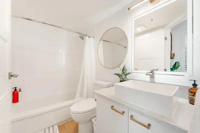 a white bathroom with a sink and a mirror at Best Location Downtown Chic Suites in Vancouver