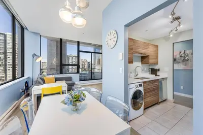 a kitchen and living room with a table and chairs and a kitchen with a stove at Best Location Downtown Chic Suites in Vancouver