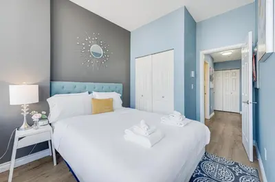 a bedroom with a white bed and a blue wall at Best Location Downtown Chic Suites in Vancouver