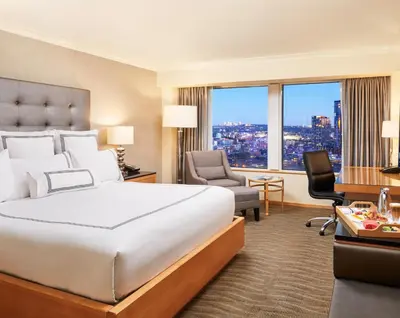 a hotel room with a bed and a desk and chair at Pan Pacific Vancouver in Vancouver