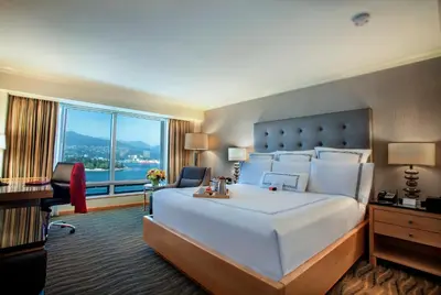 a hotel room with a large bed and a large window at Pan Pacific Vancouver in Vancouver