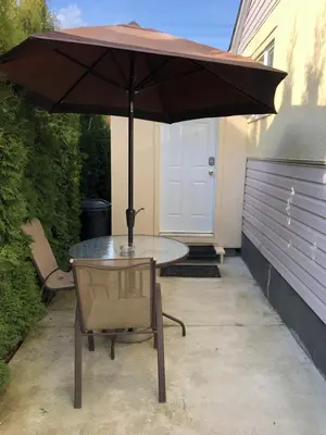 a table and a chair under an umbrella at Shady Willow Guest House - SMALL Indipendent Units with Seperate Entrance for Travellers in Chilliwack