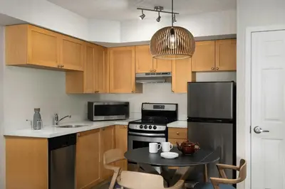 a kitchen with wooden cabinets and a black refrigerator at Delta Hotels by Marriott Whistler Village Suites in Whistler
