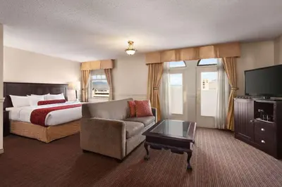 a hotel room with a bed and a couch and a television at The Plaza Hotel Downtown, Trademark Collection by Wyndham in Kamloops