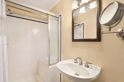 a bathroom with a sink and a shower and a mirror at The Plaza Hotel Downtown, Trademark Collection by Wyndham in Kamloops