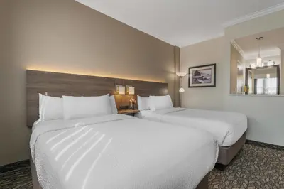a hotel room with two beds and a mirror at BEST WESTERN PLUS Carlton Plaza Hotel in Victoria