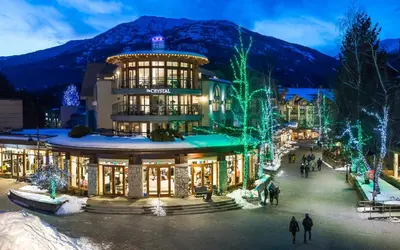 a building with christmas lights and people walking in front of it at The Crystal Lodge in Whistler