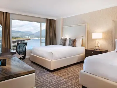 a hotel room with two beds and a balcony at Fairmont Waterfront in Vancouver