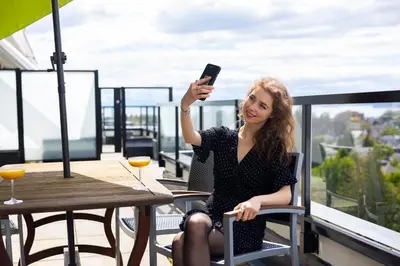 a woman sitting in a chair taking a picture on her cell phone at Oswego Hotel in Victoria