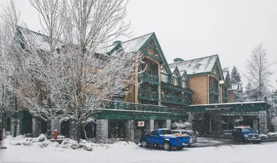 a blue truck parked in front of a building in the snow at Pinnacle Hotel Whistler in Whistler