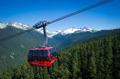 a red cable car flying through the mountains at Pinnacle Hotel Whistler in Whistler