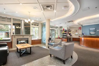 a lobby with a fireplace and chairs and a table at Pinnacle Hotel Whistler in Whistler