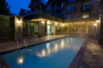 a swimming pool in front of a house at night at Pinnacle Hotel Whistler in Whistler