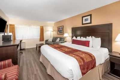 a hotel room with a large bed and a chair at Ramada by Wyndham Coquitlam in Coquitlam
